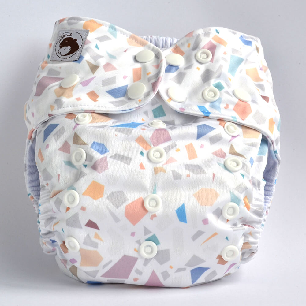 A white cloth nappy with pastel terrazzo tile design.