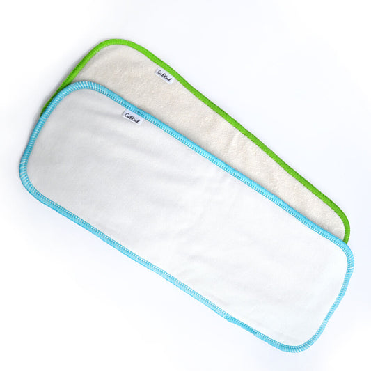 A bamboo insert with green binding and a cotton insert with blue binding.