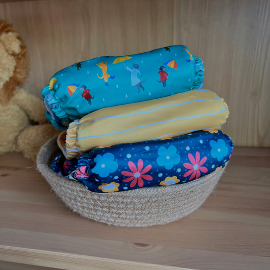 A stack of three reusable cloth nappies in a basket