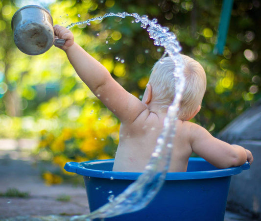 Baby splashing in an outdoor DIY bathtub