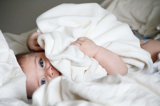 Baby wrapped in a white blanket on a bed