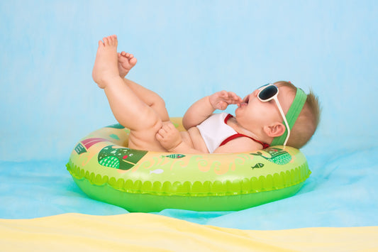 Baby sitting in a pool donut with sunglasses wearing reusable swim nappies