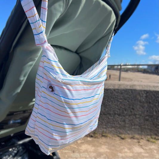Large wetbag on handles of pushchair by beach