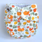A white cloth nappy with pumpkins and leaves design