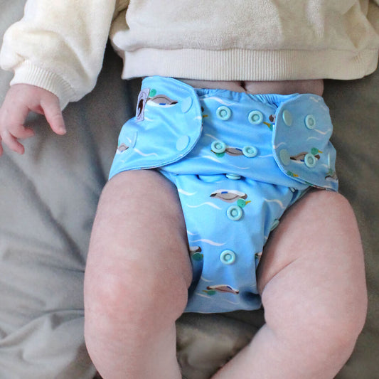 A baby wearing a blue cloth nappy with a duck design.